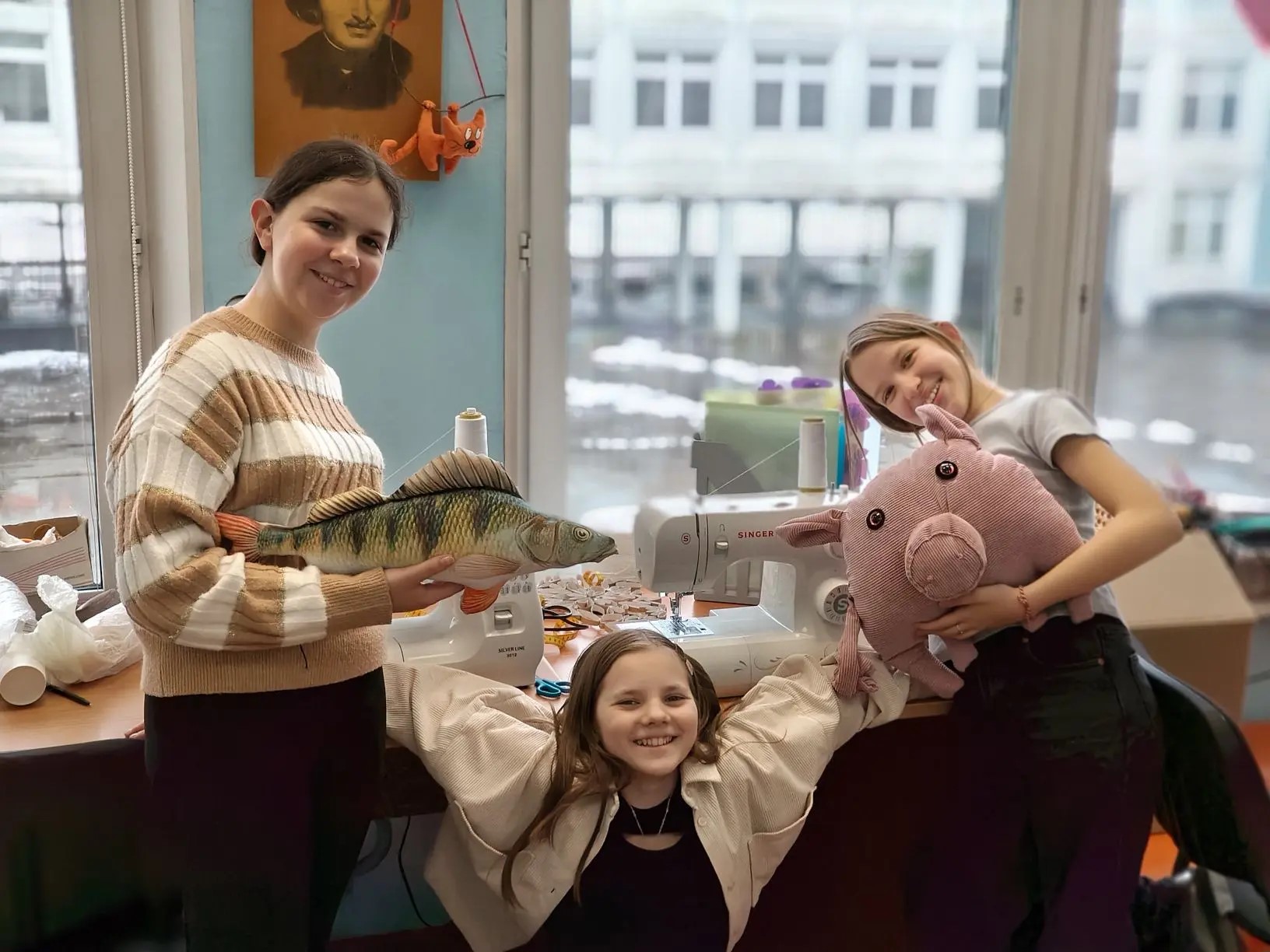 Участницы кружка с большими сшитыми игрушками у швейной машинки